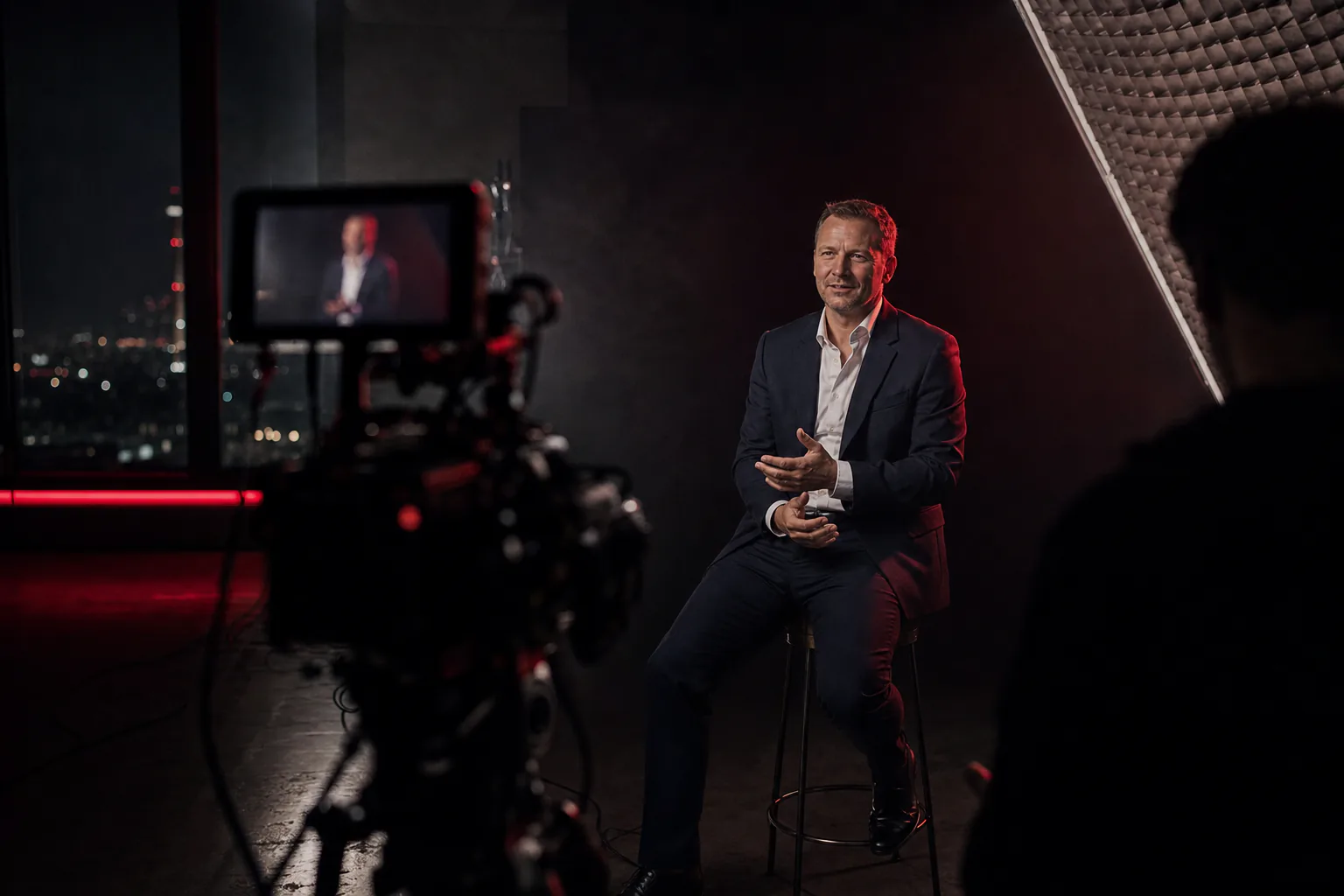 Ein Finanzberater im Anzug wird im Studio gefilmt, im Vordergrund die Kamera